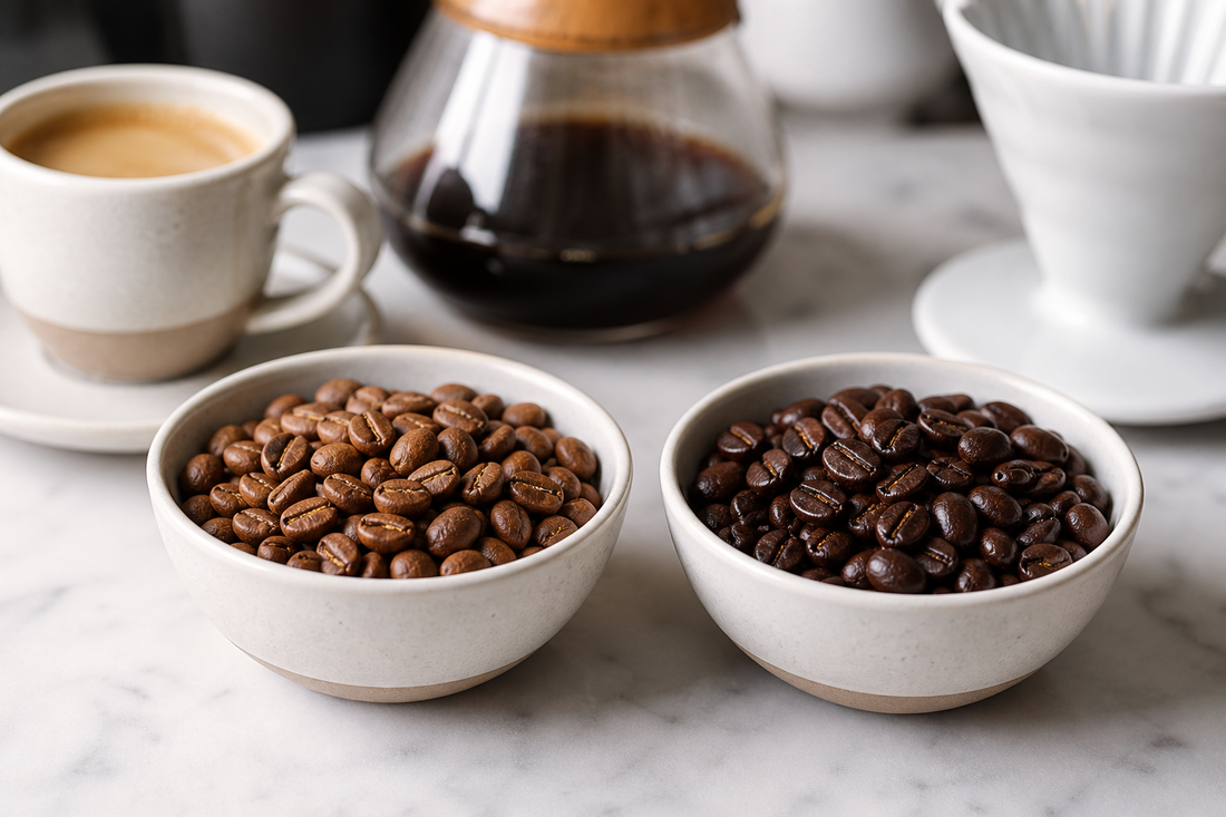 Two bowls of roasted coffee beans beside an espresso cup and a pour-over dripper on a kitchen counter