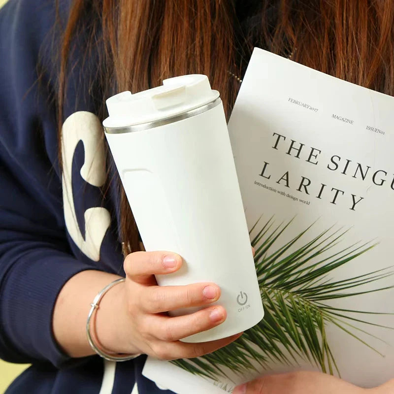 Hand holding a white insulated coffee mug