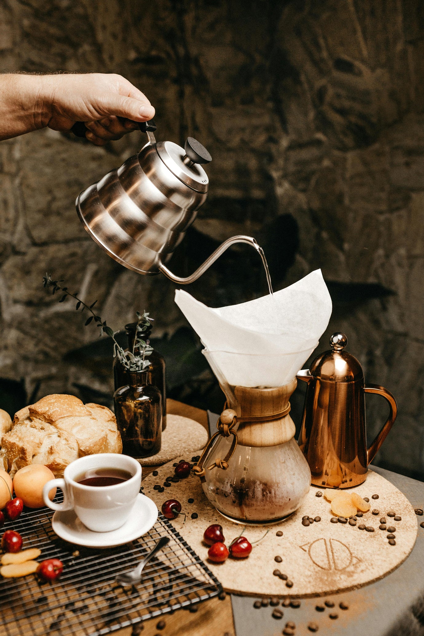 wooden table with a scale holding a coffee pot with hand pouring from above