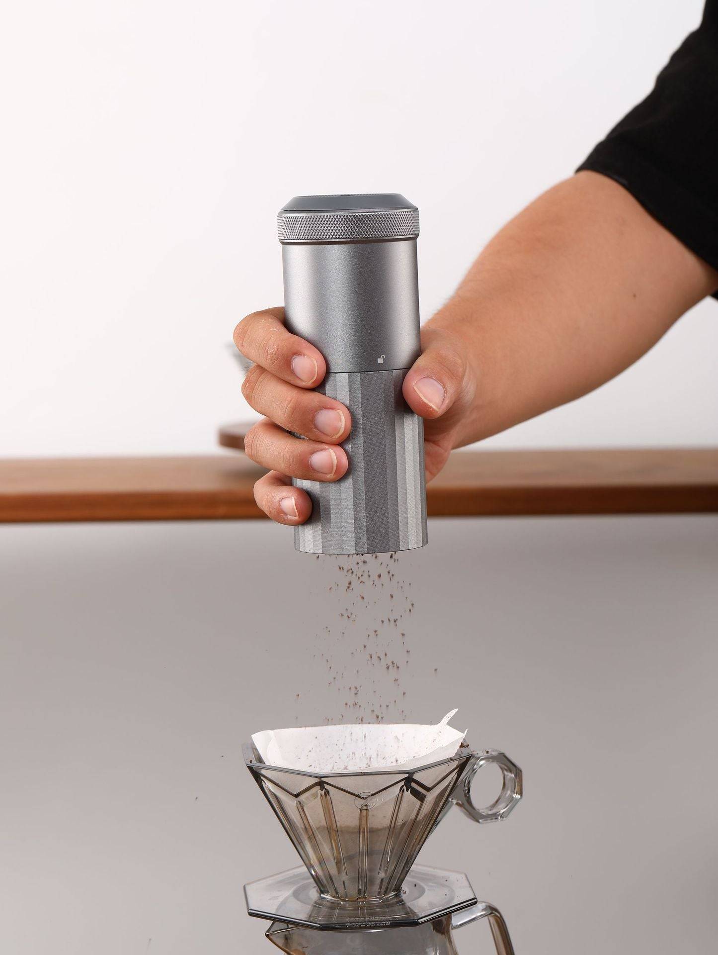 Portable Wireless Bean Grinder dispensing freshly ground coffee into a dripper. USB rechargeable and compact for effortless coffee preparation.