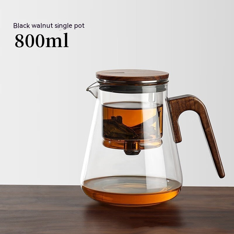 One-Click Filtering Glass Teapot with a walnut wood handle and glass liner. Features a keyless magnetic spin filter for effortless tea brewing.