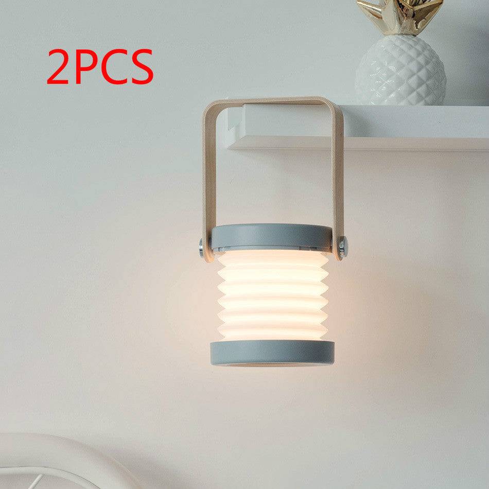 Set of two foldable LED night lights mounted on a shelf. USB rechargeable lantern with touch dimmable brightness for home and travel use.