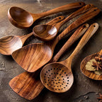 Teak wood kitchen set from Thailand featuring spoons, ladles, and turners in a glass measuring cup. Durable and eco-friendly tableware for cooking.