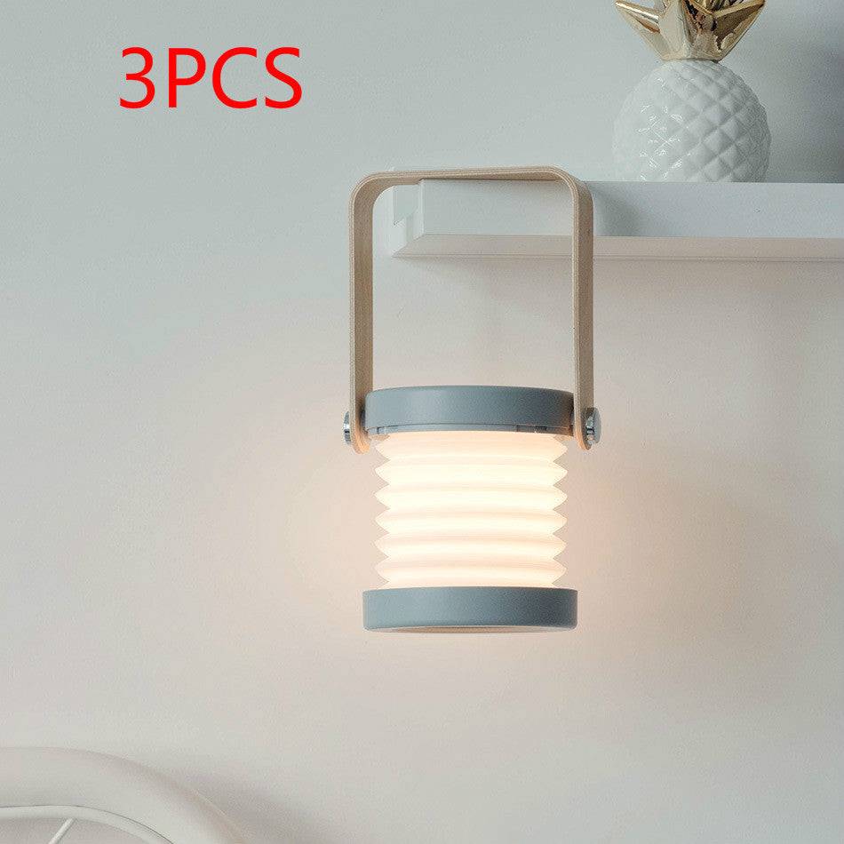 Set of three foldable LED night lights mounted on a shelf. USB rechargeable lantern with touch dimmable brightness for home decor.