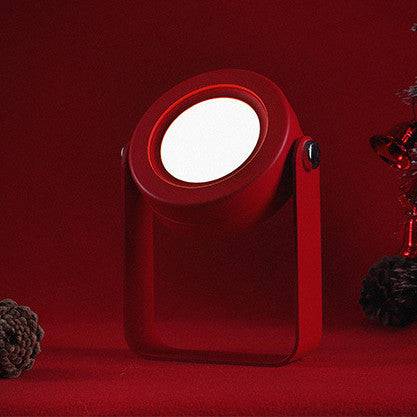 Red foldable LED night light in spotlight mode, glowing in a festive setting. USB rechargeable lamp with touch dimmable brightness control.