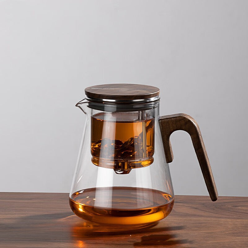 One-Click Filtering Glass Teapot with a walnut wood handle and glass liner. Features a keyless magnetic spin filter for effortless tea brewing.