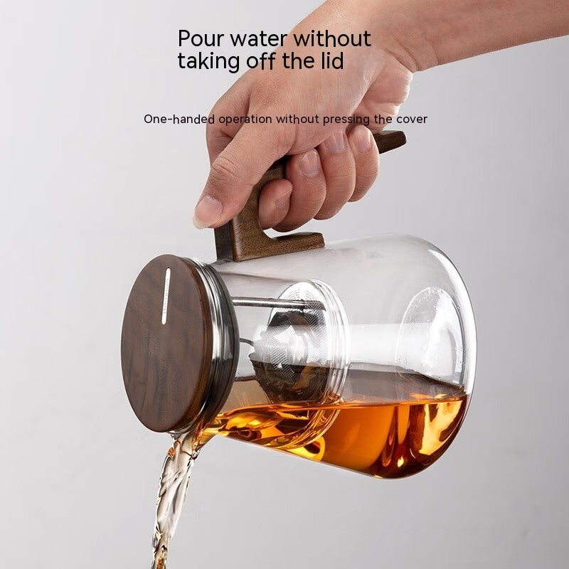 One-Click Filtering Glass Teapot with a walnut wood handle and glass liner. Features a keyless magnetic spin filter for effortless tea brewing.