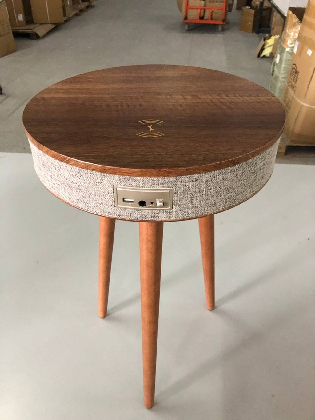 Round wooden Bluetooth speaker coffee table with wireless charging and fabric-wrapped speaker. A sleek, multifunctional furniture piece for smart homes.