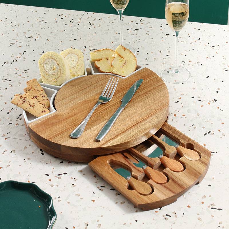 Wooden cheese board set with cutlery drawer, assorted snacks, and sparkling wine