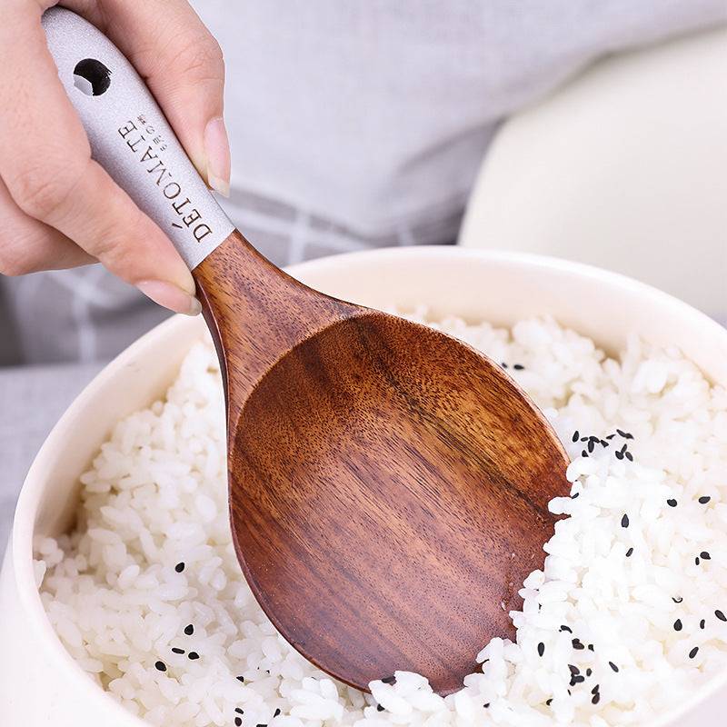 Teak lacquer rice paddle with ergonomic handle scooping white rice with black sesame seeds. Durable, eco-friendly Japanese-style kitchen utensil.