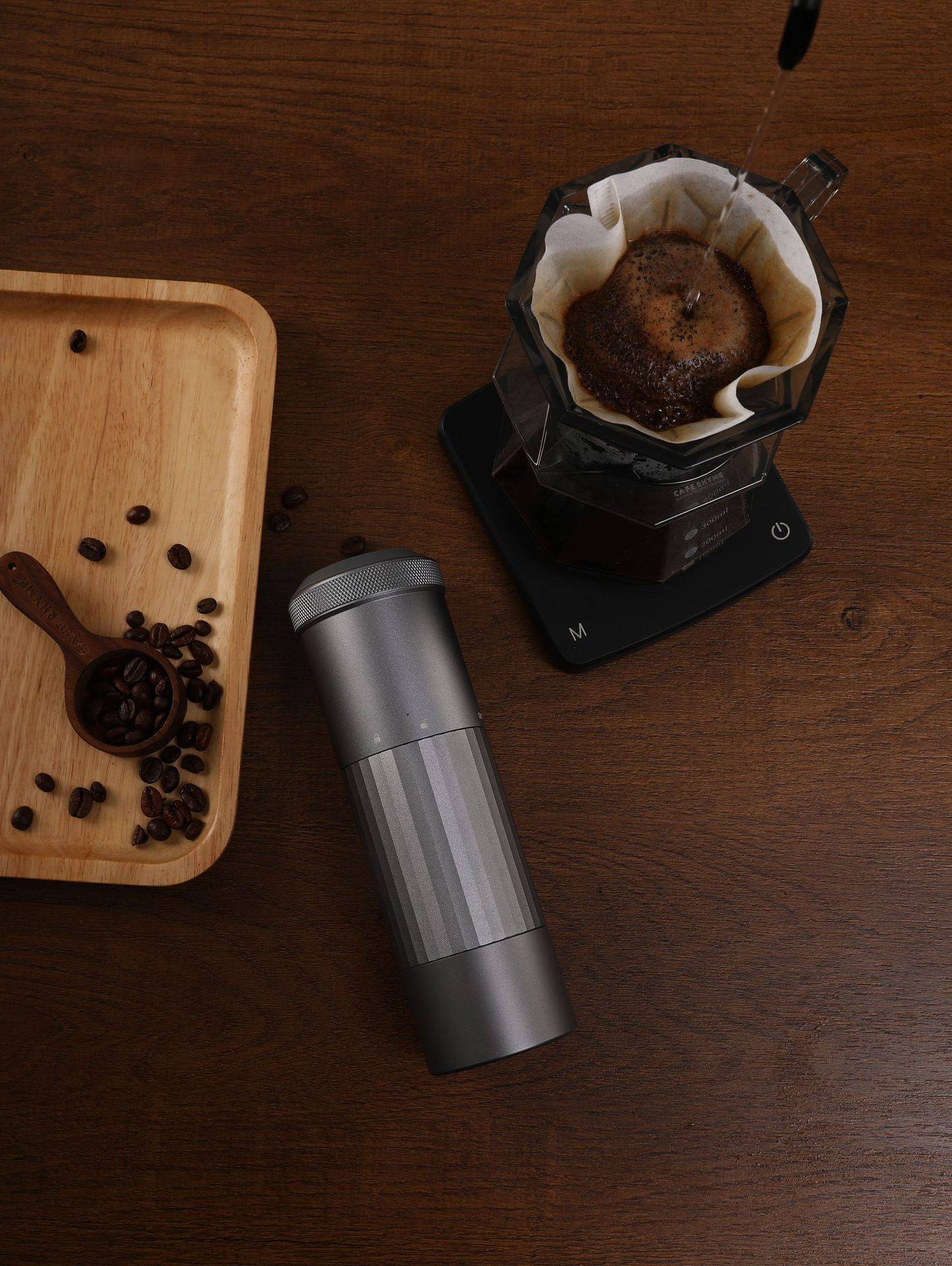 Portable Wireless Bean Grinder placed on a wooden table with coffee beans and brewing setup. Ideal for fresh coffee grinding at home.