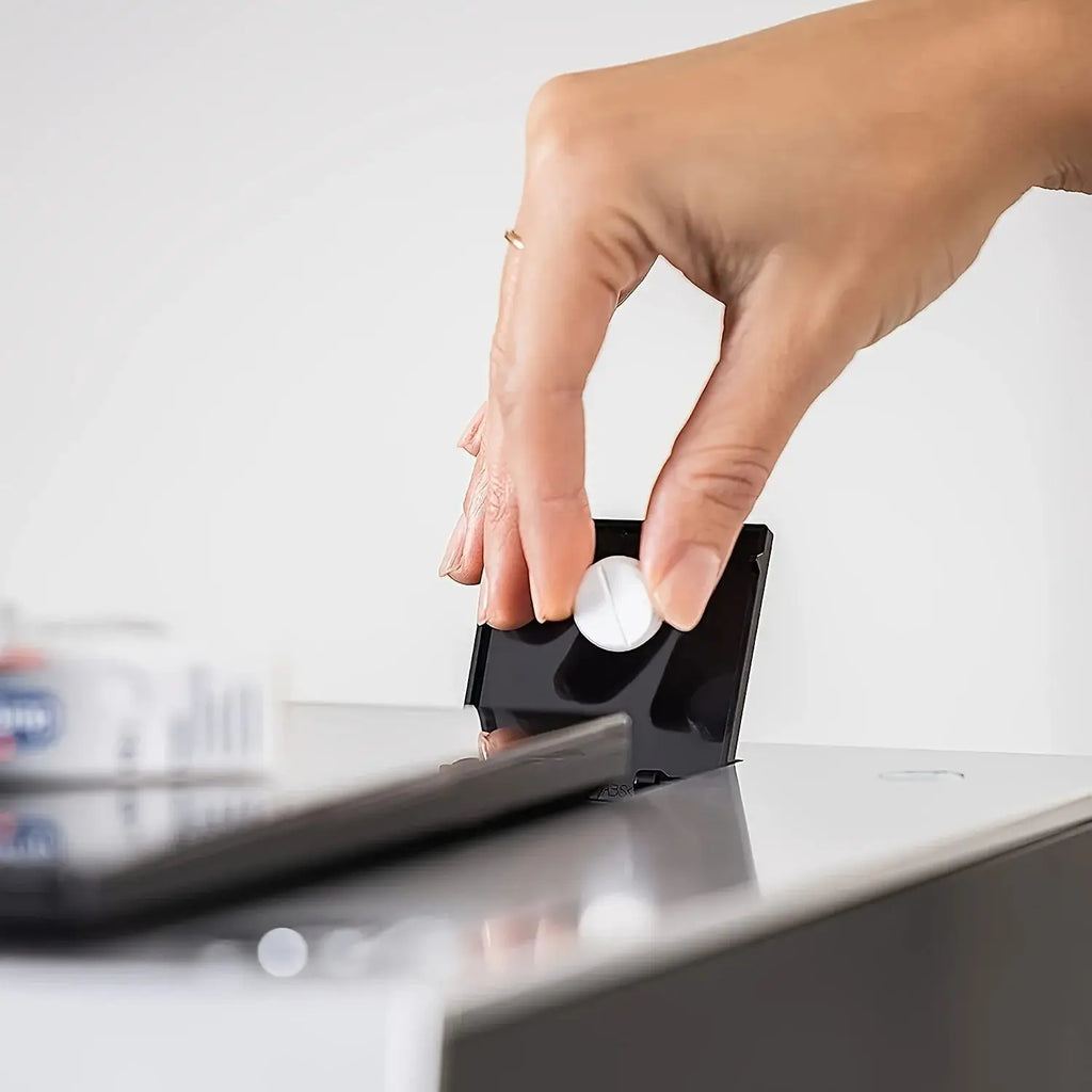 Hand placing a small black device with a circular component onto a surface.