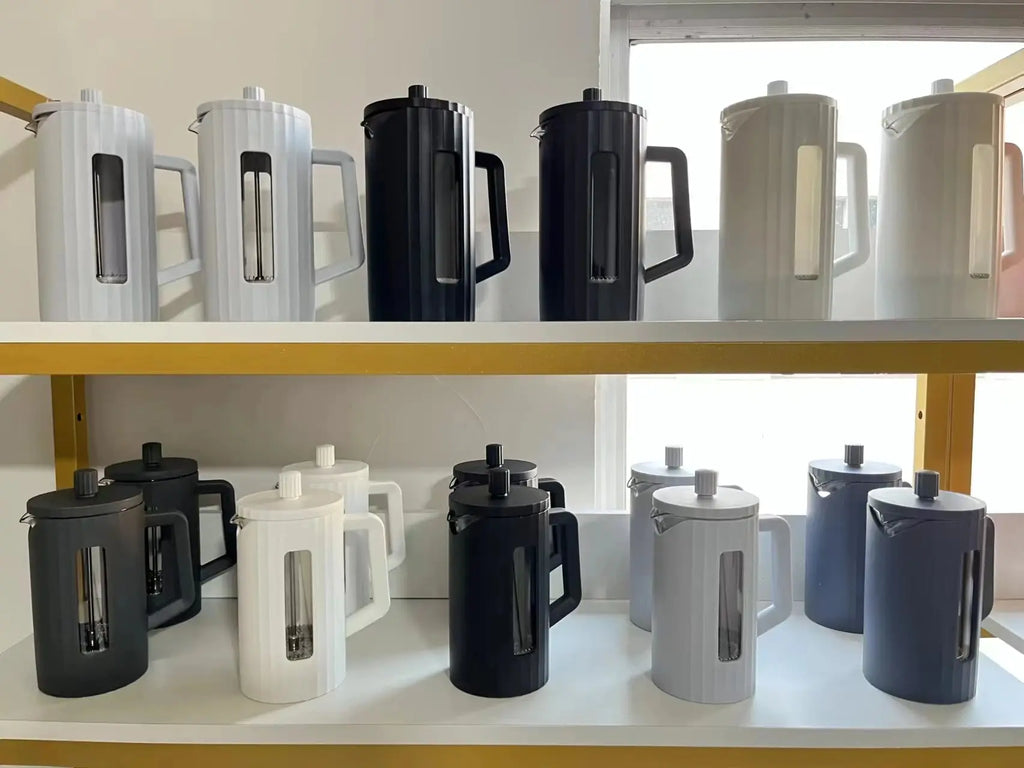 Multiple French Press Coffee Makers in black, white, and gray displayed on shelves. Stylish and functional coffee brewing appliances.