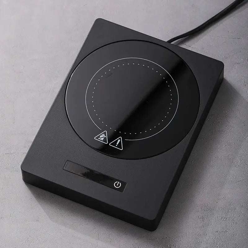 100°C Cup Heater Mug Warmer with automatic power-off, shown warming tea in a glass teapot on a wooden heating pad, ideal for hot beverages.