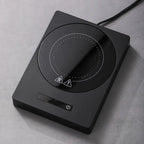 100°C Cup Heater Mug Warmer with automatic power-off, shown warming tea in a glass teapot on a wooden heating pad, ideal for hot beverages.