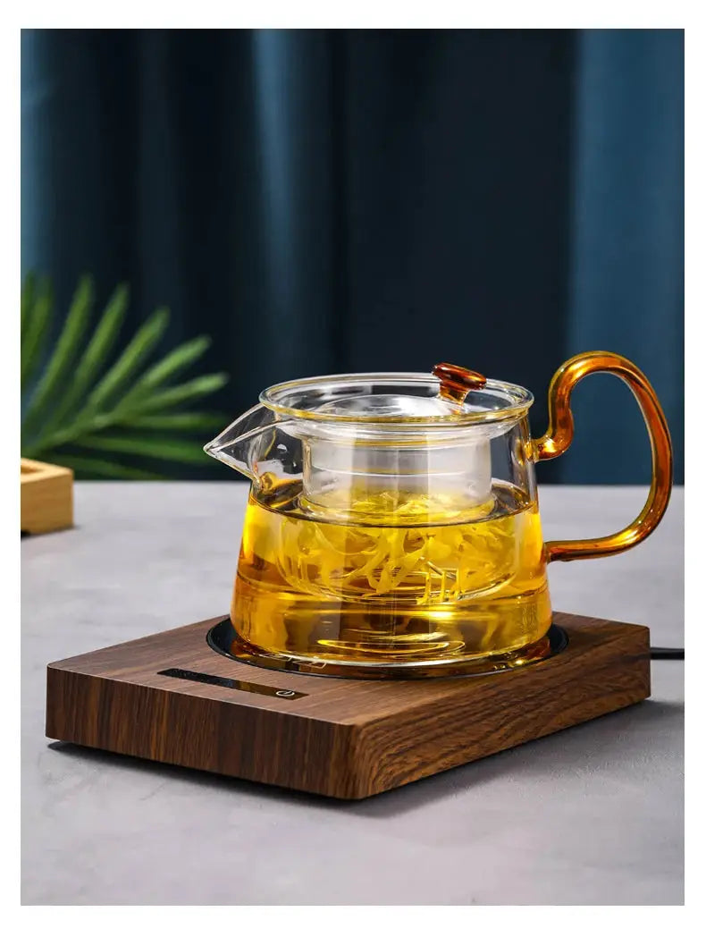 100°C Cup Heater Mug Warmer with automatic power-off, shown warming tea in a glass teapot on a wooden heating pad, ideal for hot beverages.