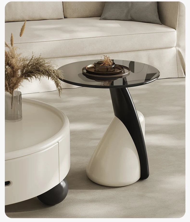 Modern side table with black glass top and white base in a living room setting.