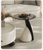 Modern side table with black glass top and white base in a living room setting.
