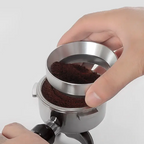 Hand using a silver coffee grinder to grind coffee beans on a white background