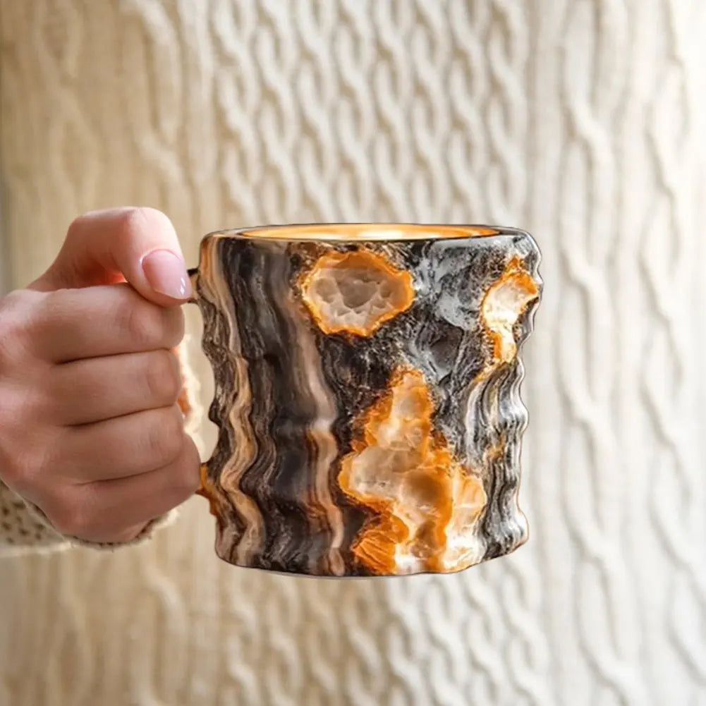 Hand holding a marbled ceramic mug against a neutral background