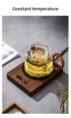 100°C Cup Heater Mug Warmer with automatic power-off, shown warming tea in a glass teapot on a wooden heating pad, ideal for hot beverages.