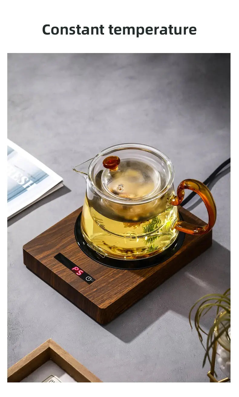 100°C Cup Heater Mug Warmer with automatic power-off, shown warming tea in a glass teapot on a wooden heating pad, ideal for hot beverages.