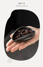 Ceramic coffee beans dosing cup with a speckled glaze finish, featuring a tapered spout for precise pouring. Ideal for measuring espresso beans with accuracy.