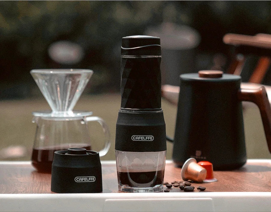 Portable 3-in-1 Cafelffe espresso maker in black, featuring a compact design, placed on a wooden surface beside coffee beans and a glass dripper.