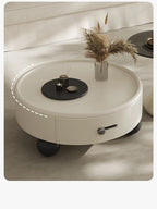 Round white coffee table with decorative items on a neutral background
