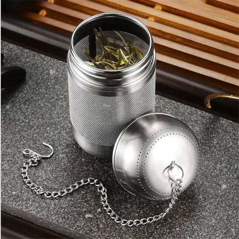 Stainless steel tea infuser with a chain, filled with loose tea leaves. Perfect for steeping fresh and flavorful tea effortlessly.