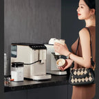 Woman holding a coffee cup next to a coffee machine in a kitchen setting