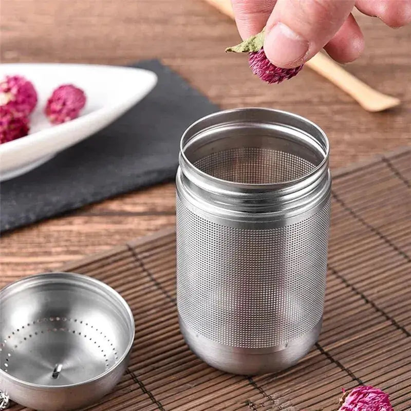 Tea strainer with fine mesh, being filled with dried flowers for herbal tea. Stainless steel design ensures durability and easy cleaning.