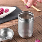 Tea strainer with fine mesh, being filled with dried flowers for herbal tea. Stainless steel design ensures durability and easy cleaning.