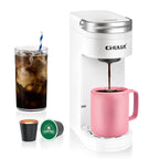 Electric travel coffee maker in white, brewing coffee into a pink mug, with K-Cup capsules alongside an iced coffee glass.