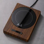 100°C Cup Heater Mug Warmer with automatic power-off, shown warming tea in a glass teapot on a wooden heating pad, ideal for hot beverages.