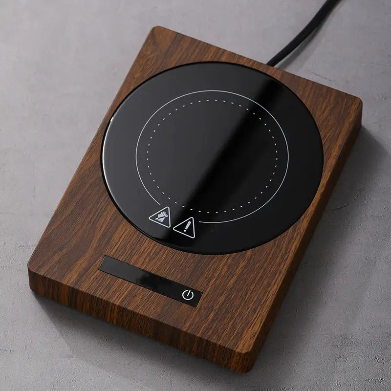 100°C Cup Heater Mug Warmer with automatic power-off, shown warming tea in a glass teapot on a wooden heating pad, ideal for hot beverages.
