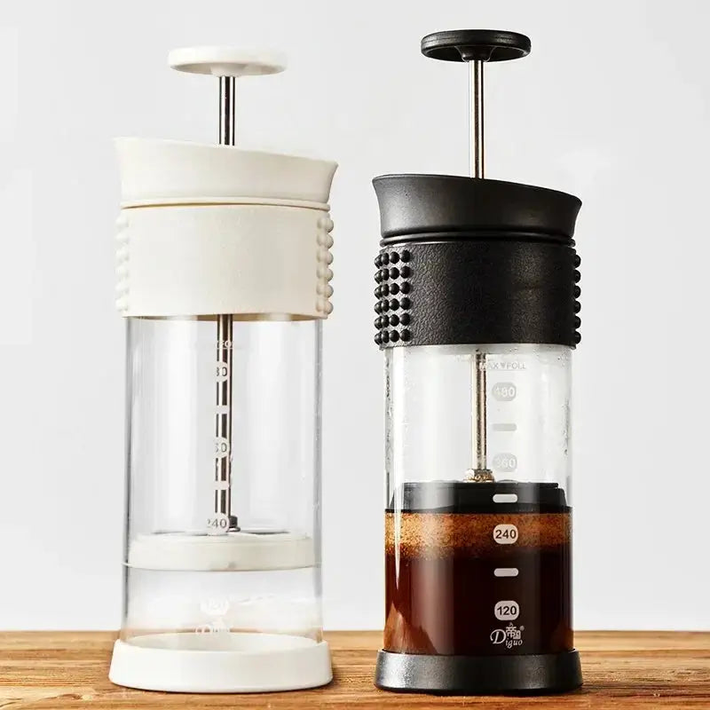 Two coffee presses, one white and one black with a textured handle, on a wooden surface.