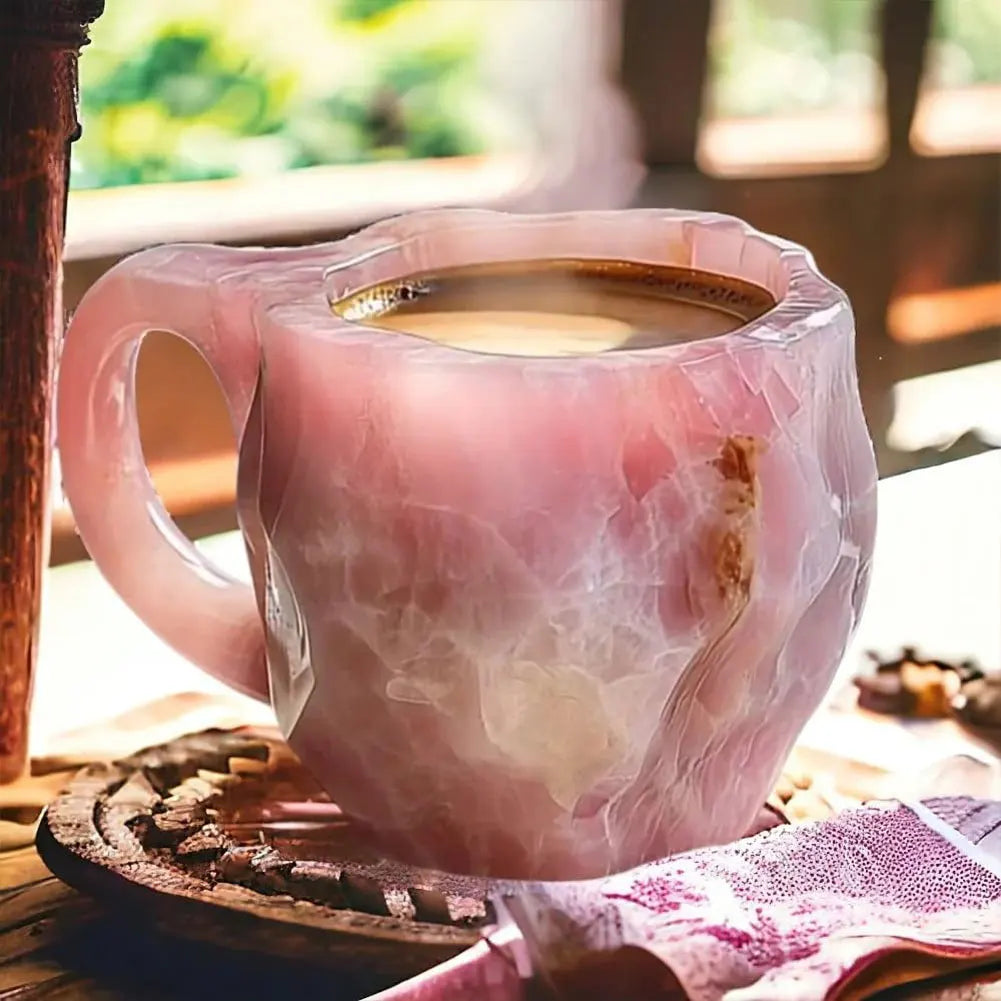 Pink marble-patterned mug with steaming coffee on a wooden coaster.