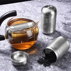 Stainless steel tea strainer infusing tea in a glass teapot. Features a fine mesh and chain for easy brewing and removal.