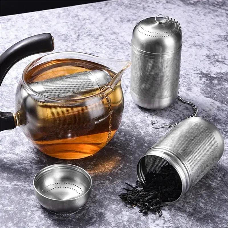Stainless steel tea strainer infusing tea in a glass teapot. Features a fine mesh and chain for easy brewing and removal.