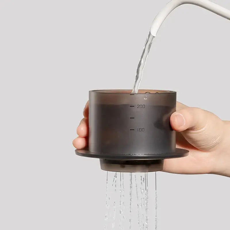 Hand pouring water into the TIMEMORE SimpleDrip Water Dropper, designed for precise and even coffee brewing.