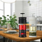 Two portable coffee makers on a wooden table with a blurred kitchen background