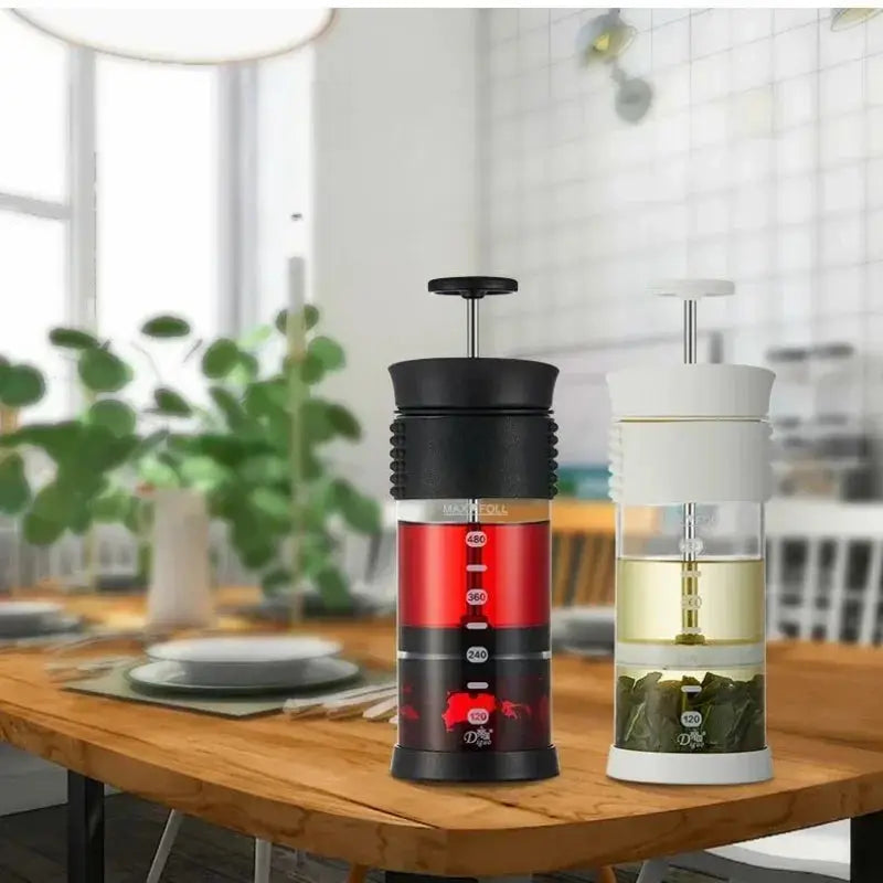 Two portable coffee makers on a wooden table with a blurred kitchen background
