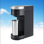 Compact black electric coffee maker with a stainless steel cup positioned underneath, set against a bright blue sky.
