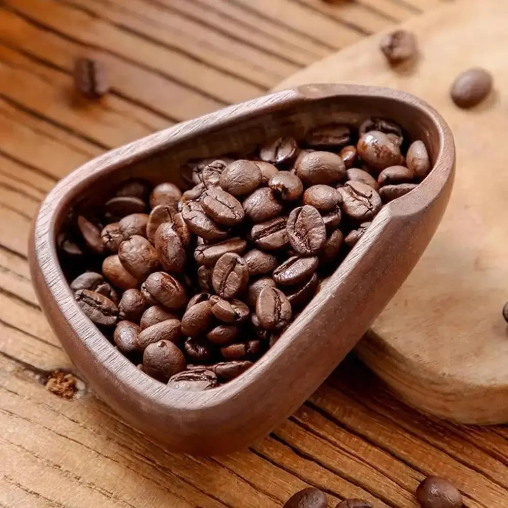 Wooden scoop filled with coffee beans on a wooden surface