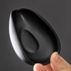 Black ceramic coffee beans dosing cup with a unique curved design and tapered spout for precise pouring. Ideal for espresso and coffee bean measuring.