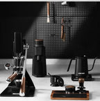 Modern coffee brewing equipment set with espresso maker, grinder, kettle and tamper on countertop