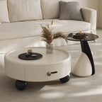 Round white coffee table with decorative items in a living room setting.