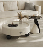 Round white coffee table with a drawer in a living room setting.