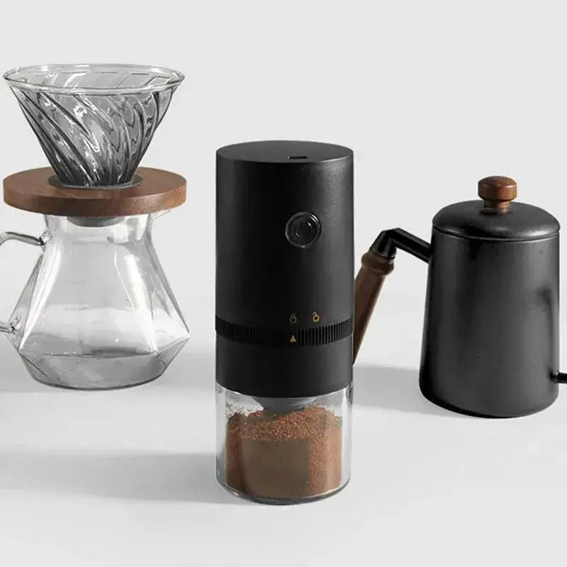 Portable electric coffee grinder placed beside a pour-over coffee setup, ideal for home brewing and fresh coffee preparation.